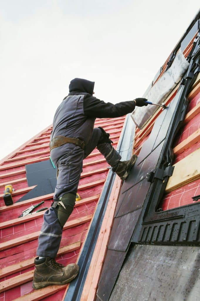 A roofer replacing the tiles on a house roof.