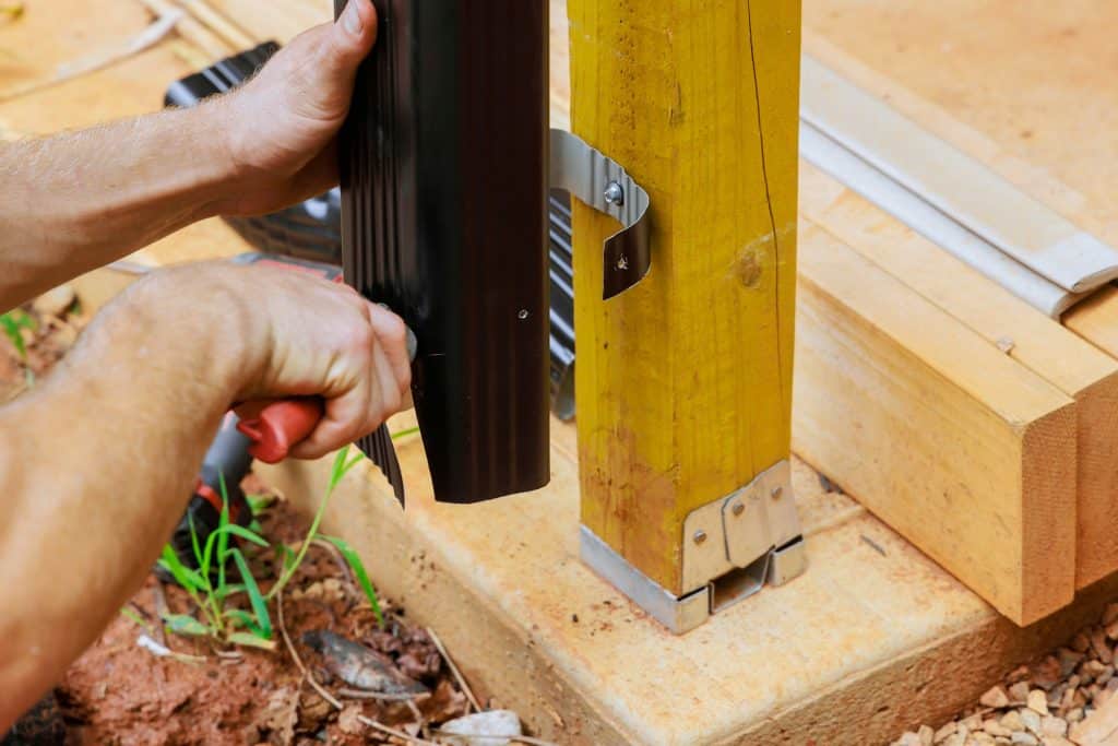 Before installing aluminum rain gutters, a worker cuts them with metal shears