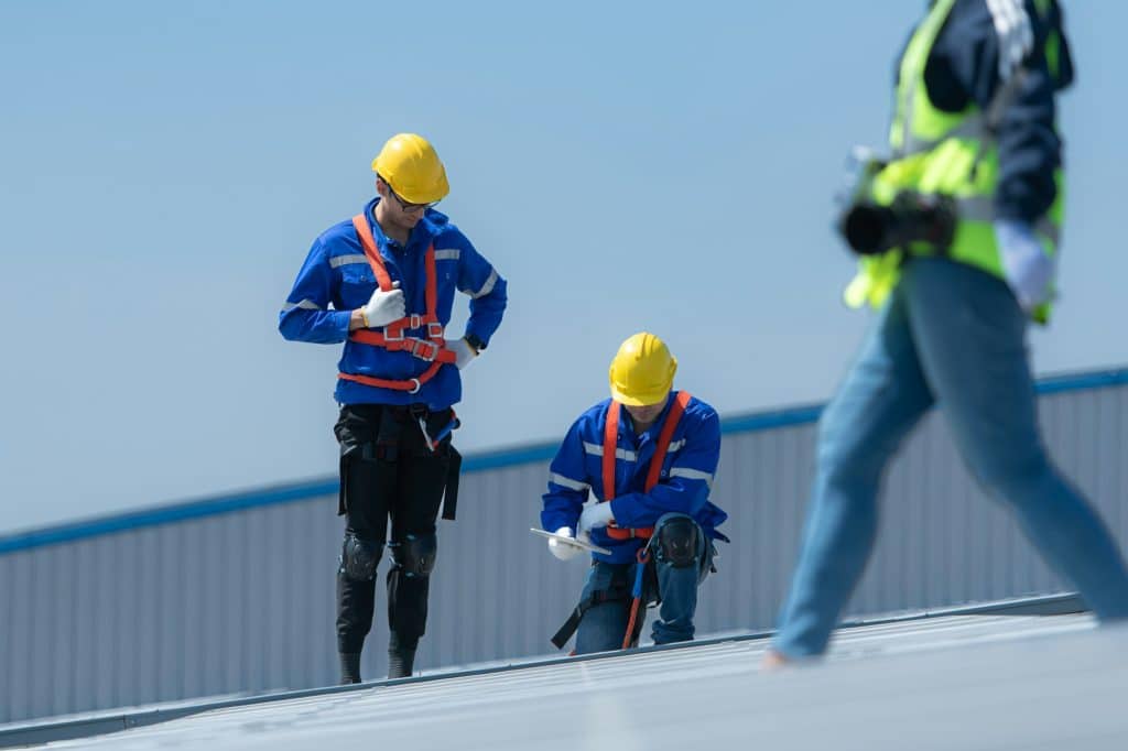 Both of technicians is installing solar panels on the roof of the warehouse